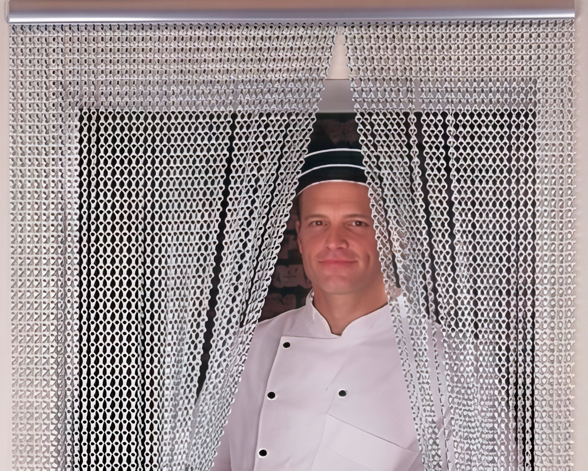 Koch in Arbeitskleidung steht hinter einem Fliegenvorhang