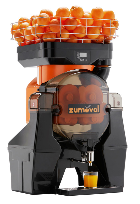 Automatische Zitrussaftpresse mit einem Gitter voller Orangen und einem Glas frischem Orangensaft.